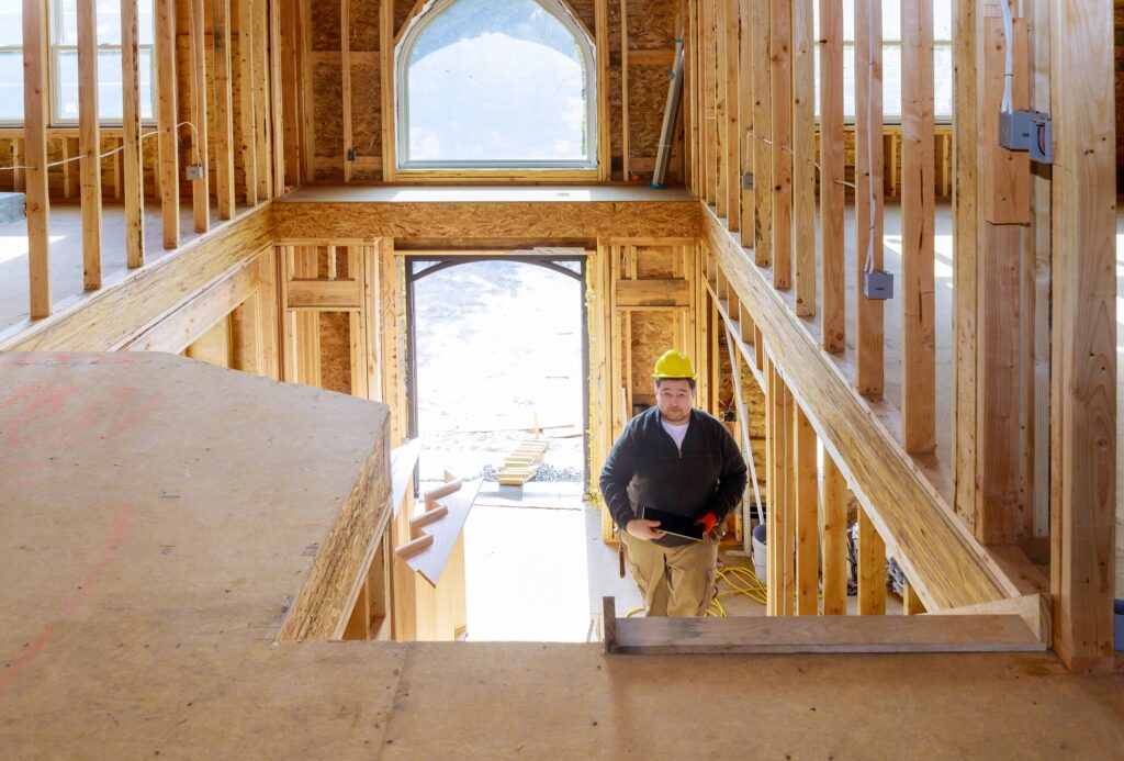 New construction house builder in hard hat walking in the holding tablet PC