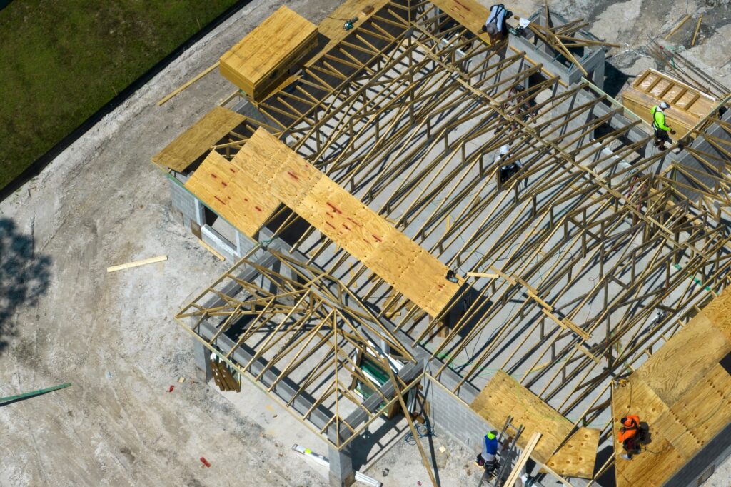 Professional builders working on roof construction of unfinished suburban home